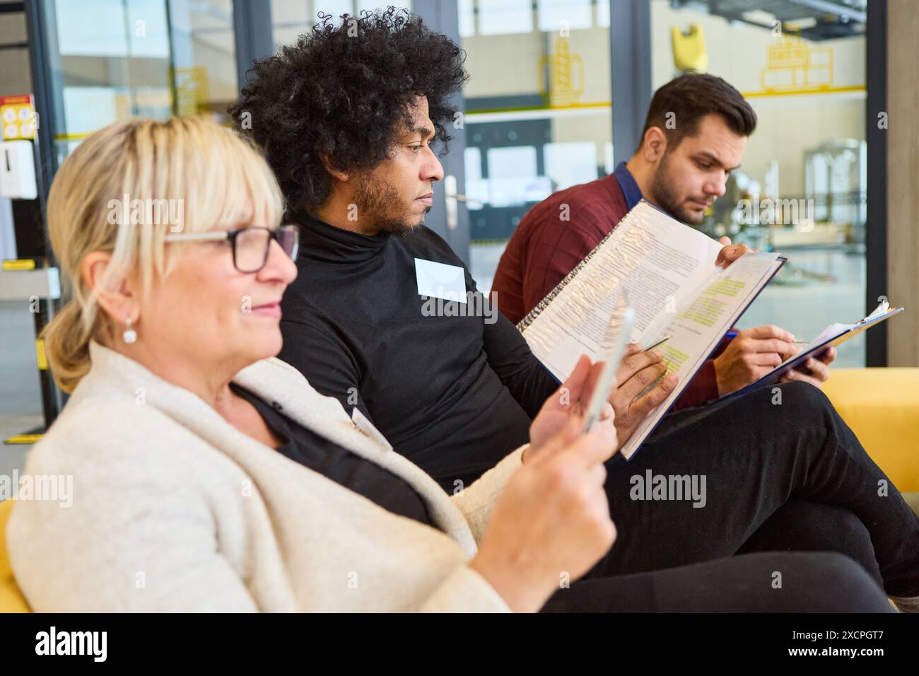 Three professionals attentively engaged in a workshop, focusing on robotics and process automation development, inspecting notes and manuals. Stock Photo