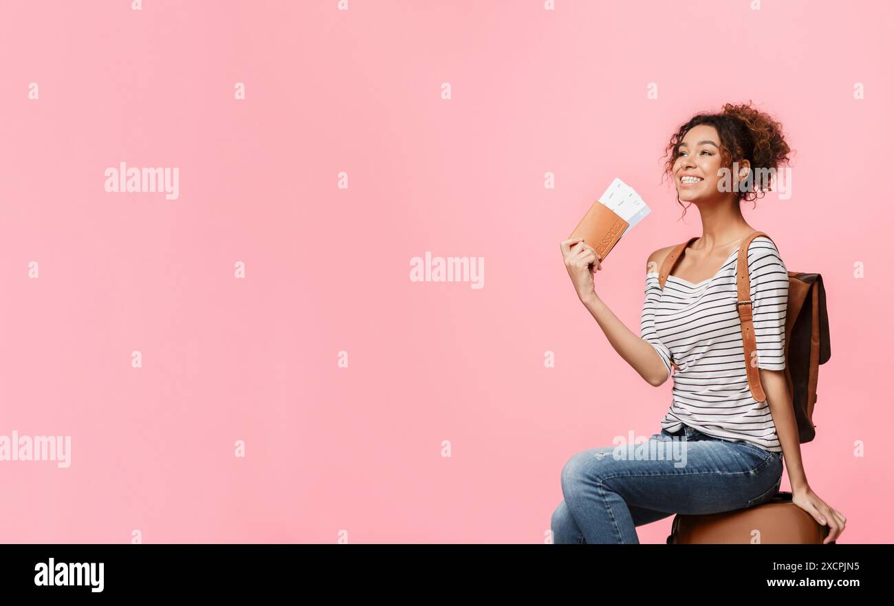 African-american woman with tickets sitting on suitcase Stock Photo - Alamy