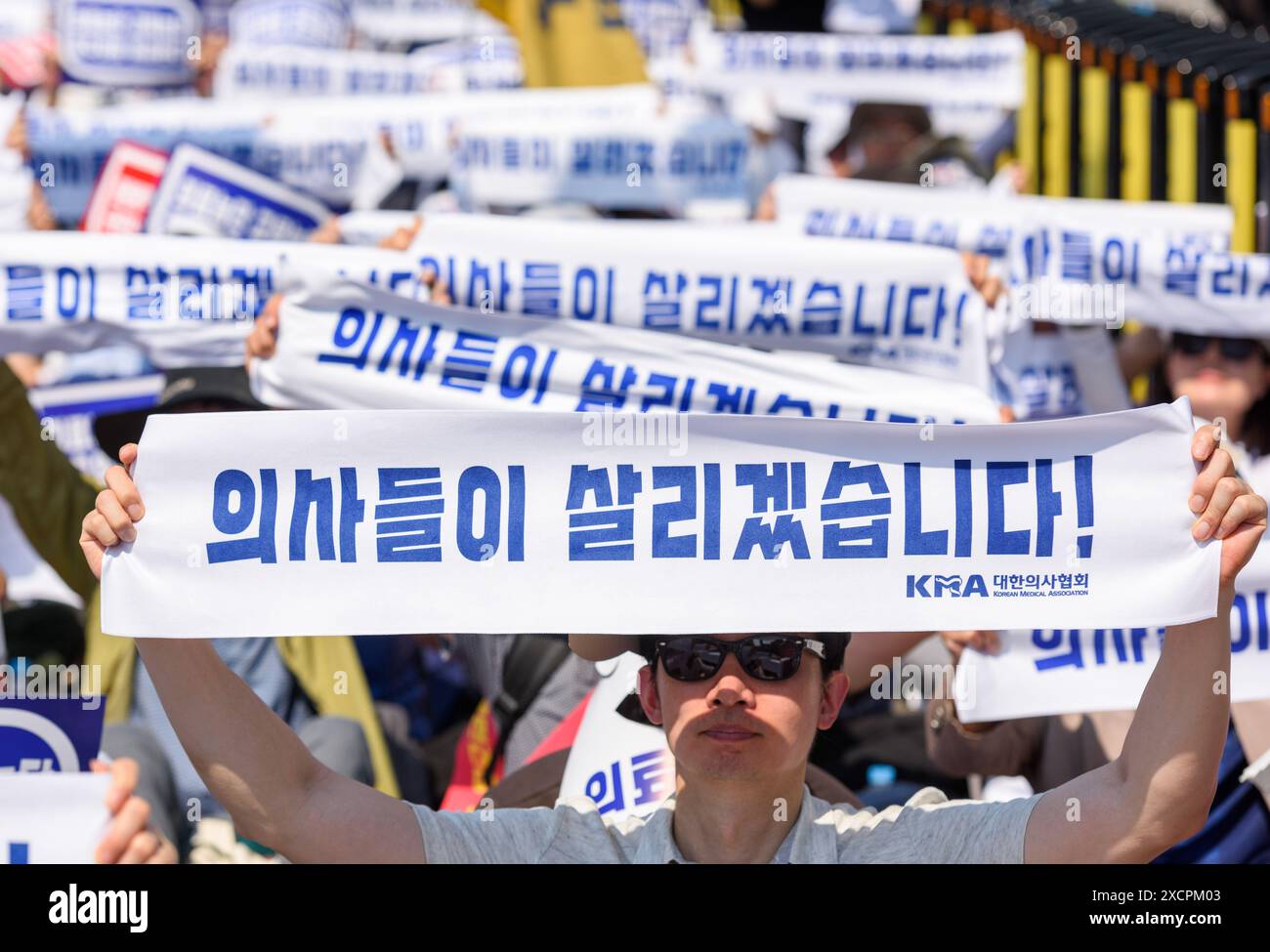 South Korean doctors hold signs protesting the increase in the medical school enrollment rate. The rally coincides with a one-day nationwide strike by local doctors, led by the Korean Medical Association. South Korea's largest lobby group of community doctors on June 18 threatened to begin an indefinite walkout starting June 27 unless the government accepts its demands, including revisiting the issue of increasing medical school admissions. Lim Hyun-taek, head of the Korea Medical Association, made the remarks at a rally of some 10,000 doctors earlier in the day, when some community doctors st Stock Photo