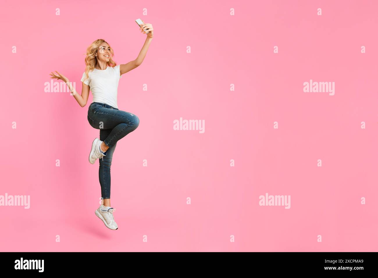 Happy Woman Taking Selfie While Jumping in the Air Stock Photo