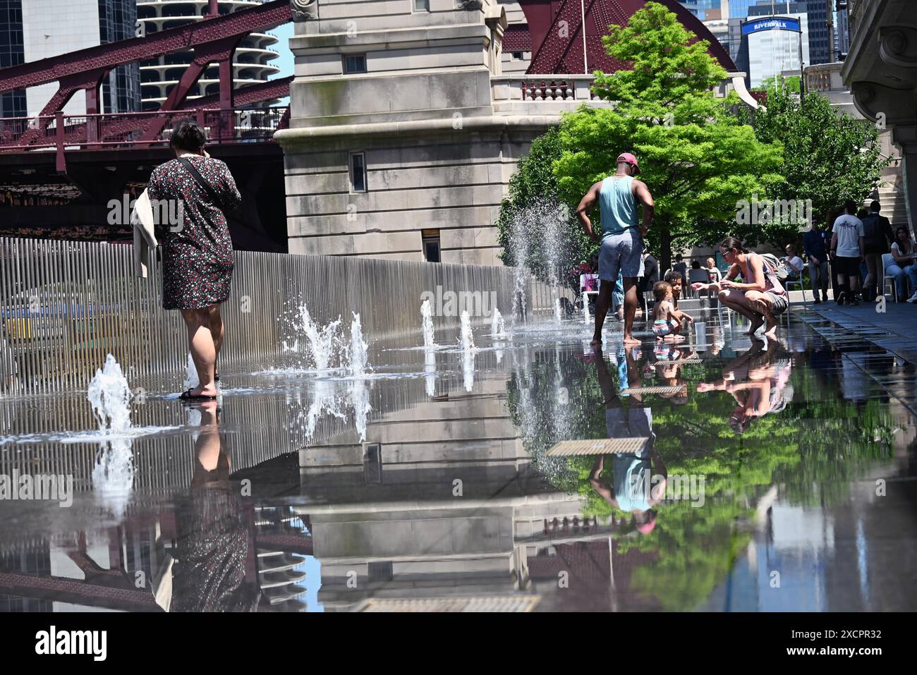 Adults and kids alike cool off on the fountains on the Chicago Riverwalk in a section known as the Water Plaza. Stock Photo