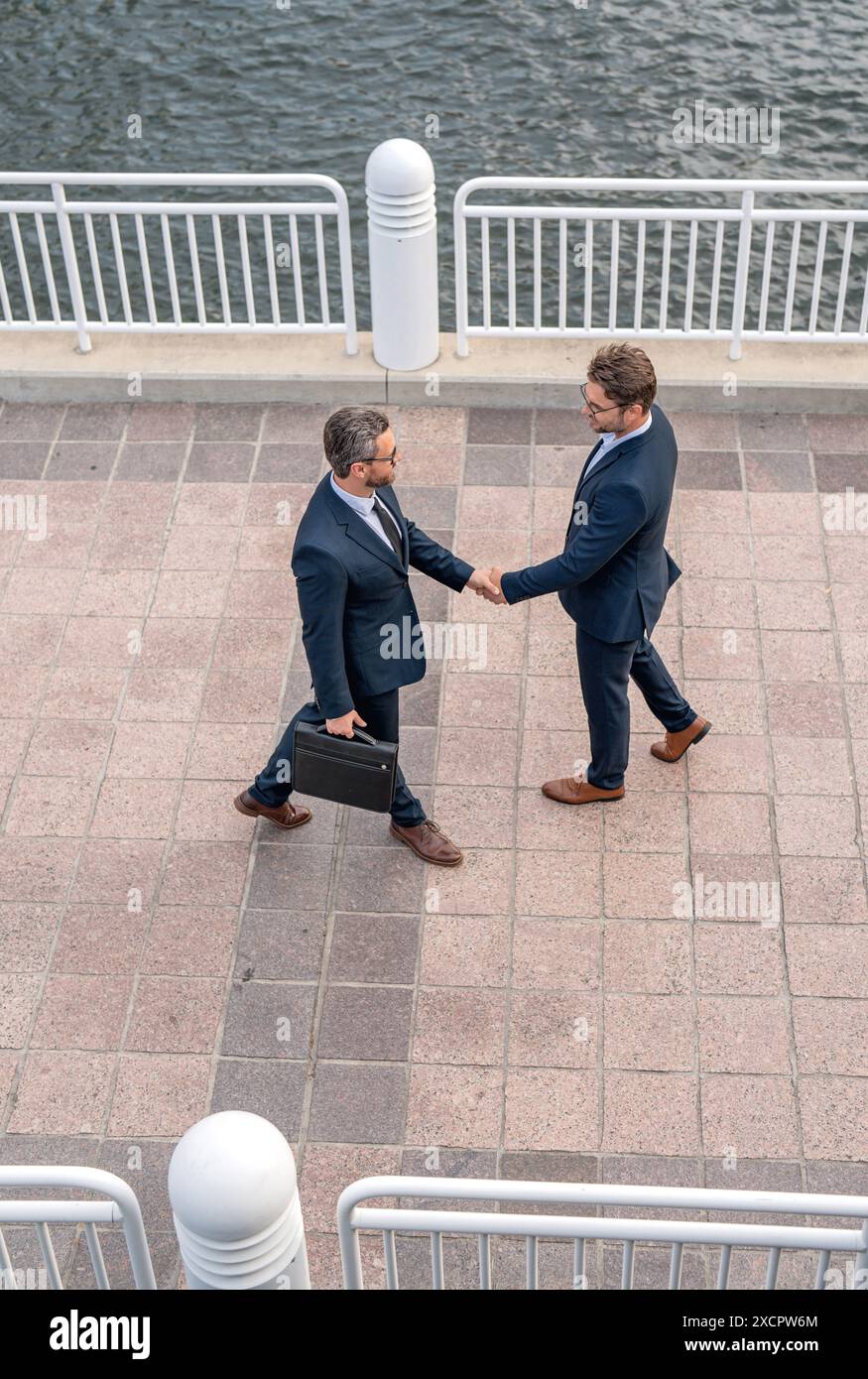 Handshake with partner in the city for greeting. Businessmen in suit shaking hands outdoors. Handshake between two businessmen. wo business men had Stock Photo