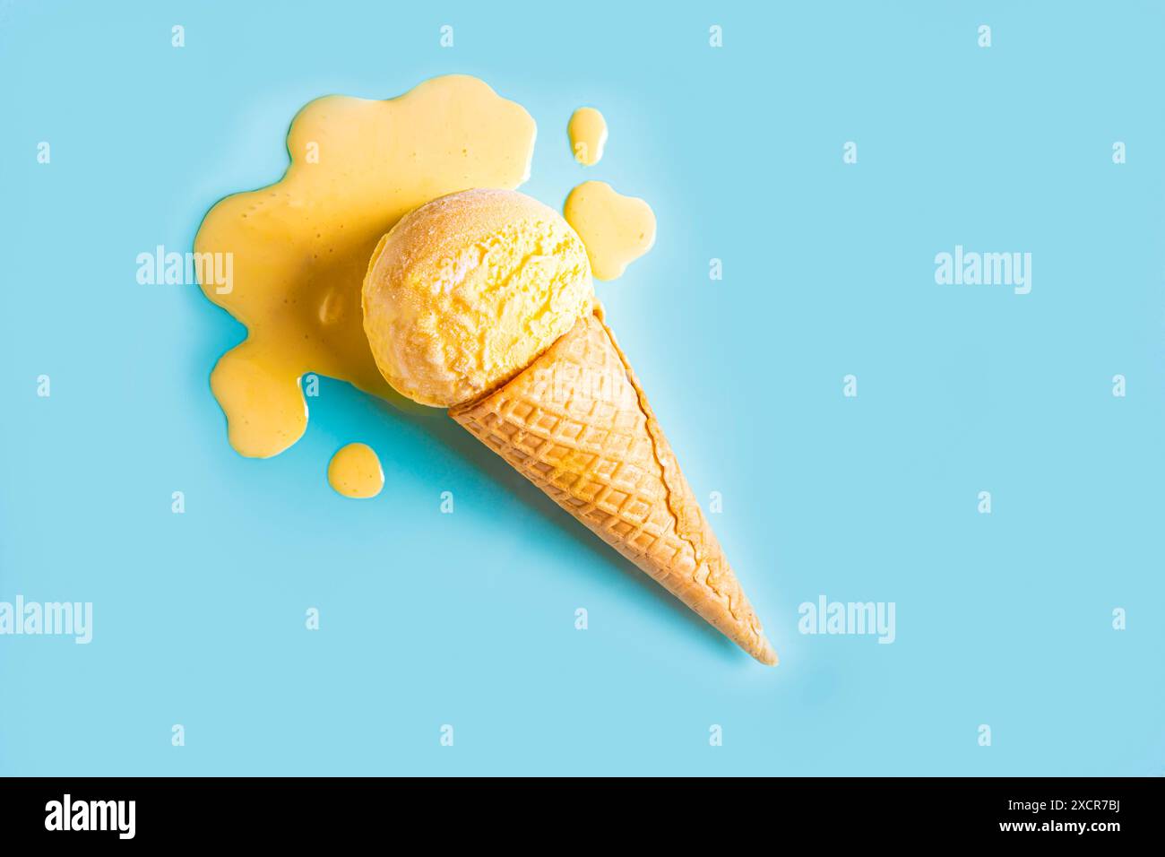 Yellow ice cream melting and spilling in waffle cone on pastel blue background. Minimal trendy creative summer food concept layout. Melted scoop of fr Stock Photo