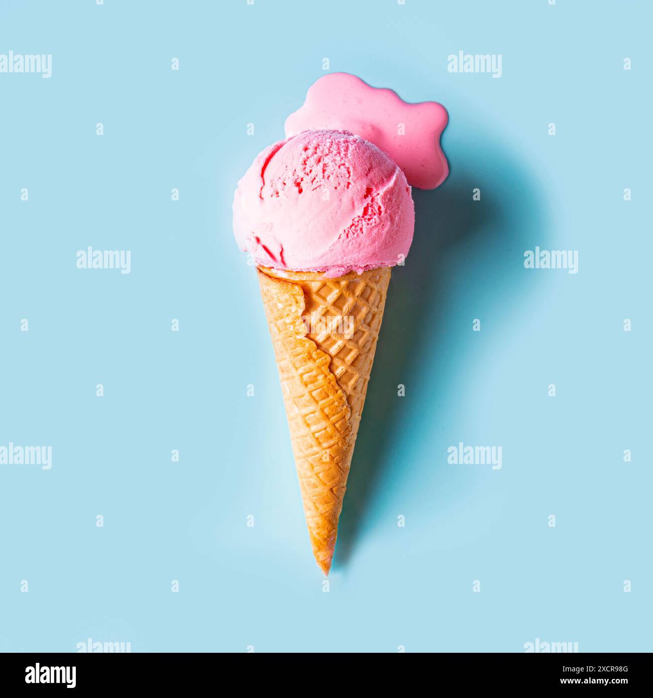Pink ice cream melting and spilling in waffle cone on pastel blue ...