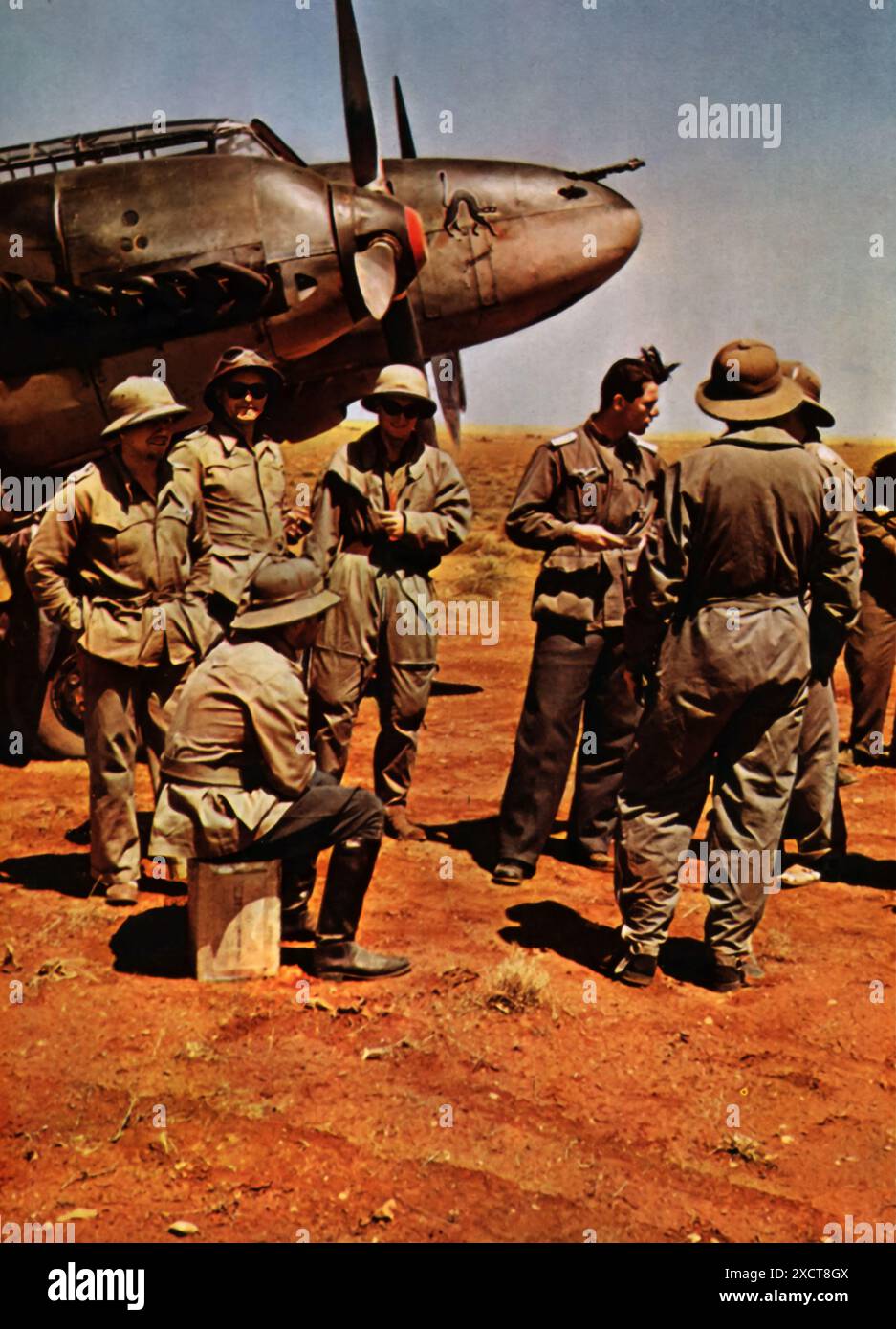 A photograph shows Luftwaffe officers in Africa, dressed in tropical gear, reviewing a mission report on enemy engagements during the Second World War. These detailed reports were crucial for evaluating the success of air missions, planning future operations, and adapting strategies based on enemy movements and defenses. Stock Photo