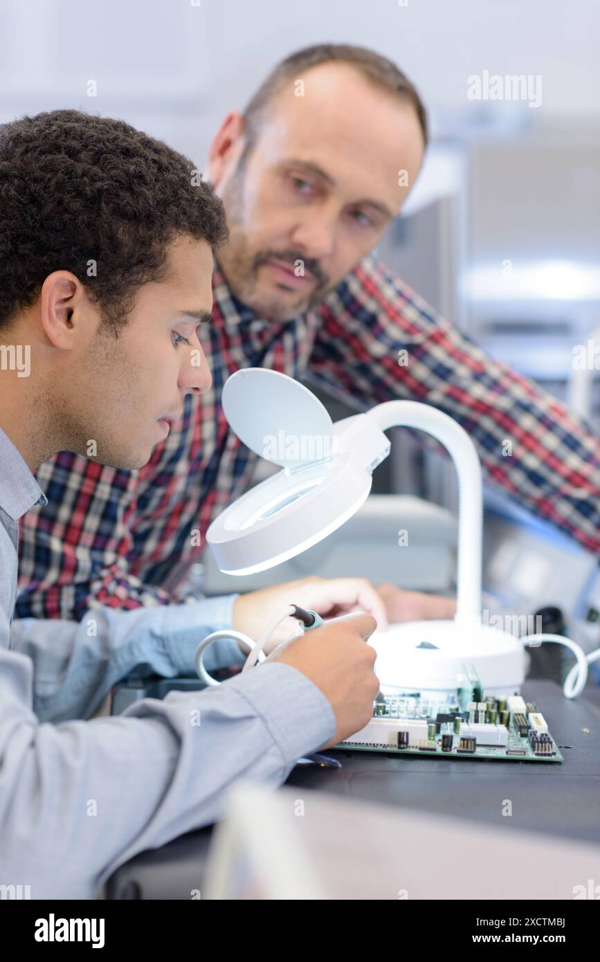 technician using magnifying glass for analyzing computer mainboard Stock Photo