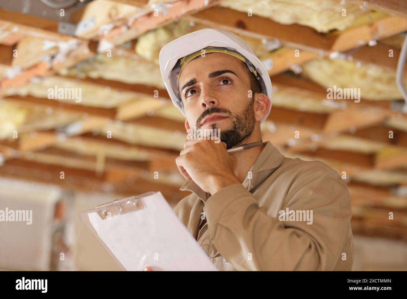 builder thinking about something while holding clipboard Stock Photo