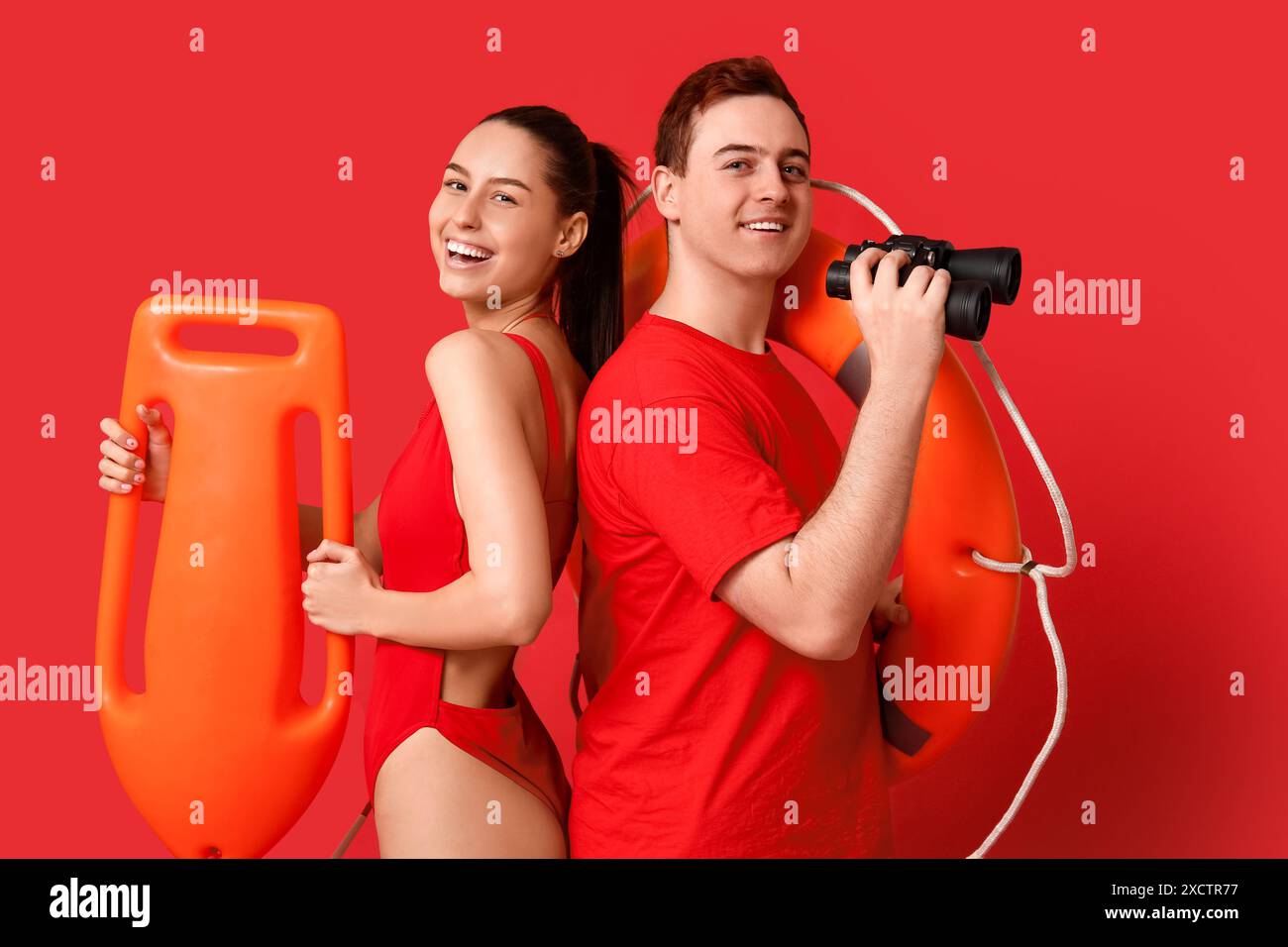 Lifeguards with ring buoy, rescue tube and binoculars on red background Stock Photo