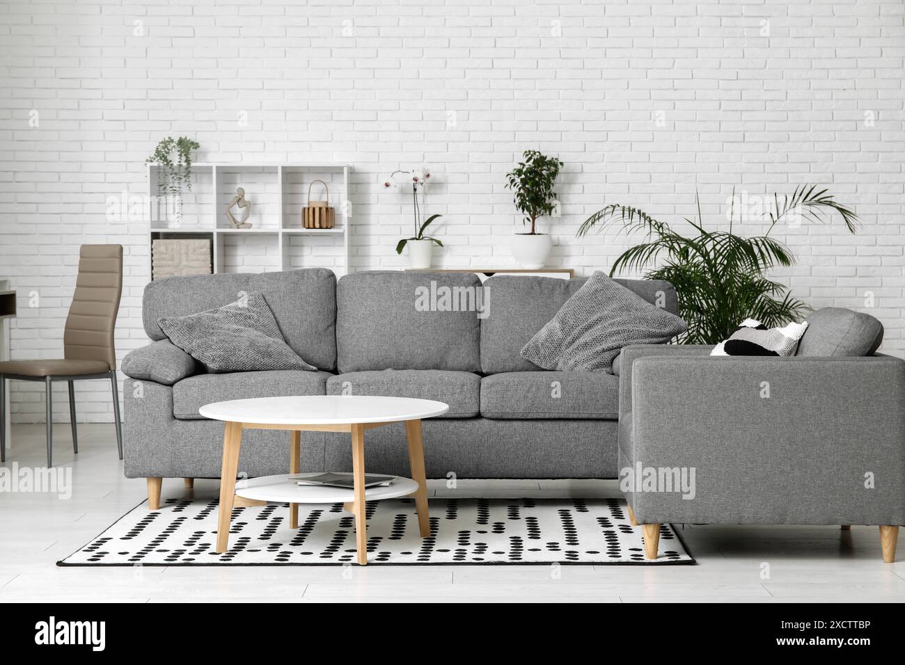 Interior of stylish living room with grey sofa, armchair and table ...