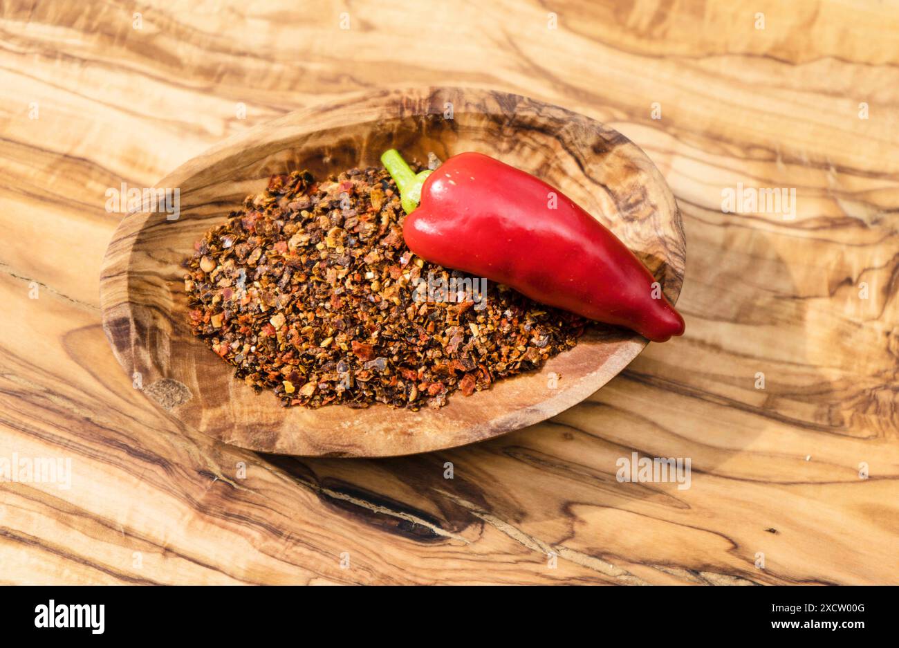 Chilli peppers and crushed chilli peppers on a wooden board Stock Photo