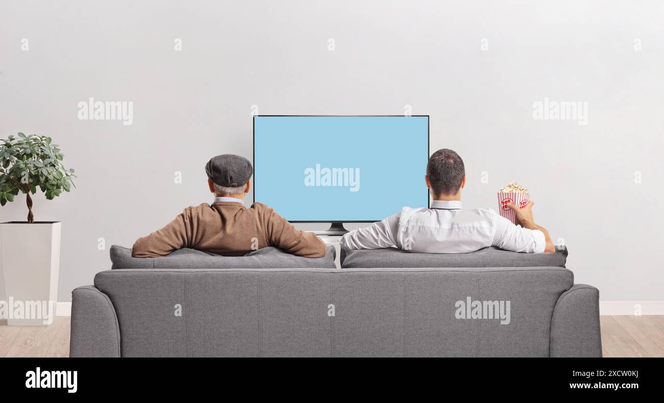 Rear view shot of ederly father and son watching tv seated on a sofa Stock Photo