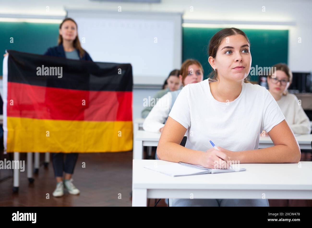 High school teacher holds the flag of Germany in her hands and talks ...