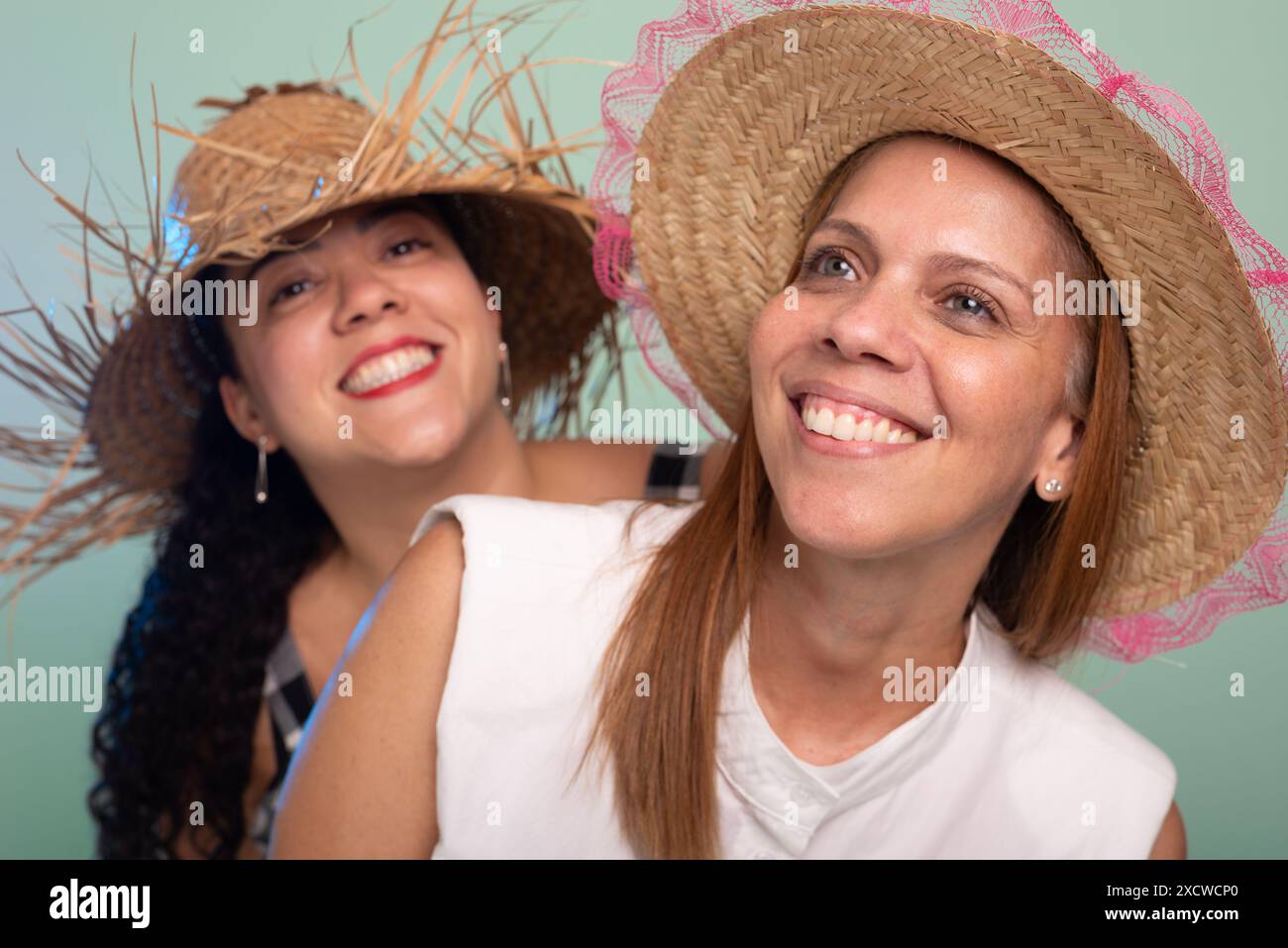Portrait of two smiling young beautiful women wearing traditional straw ...