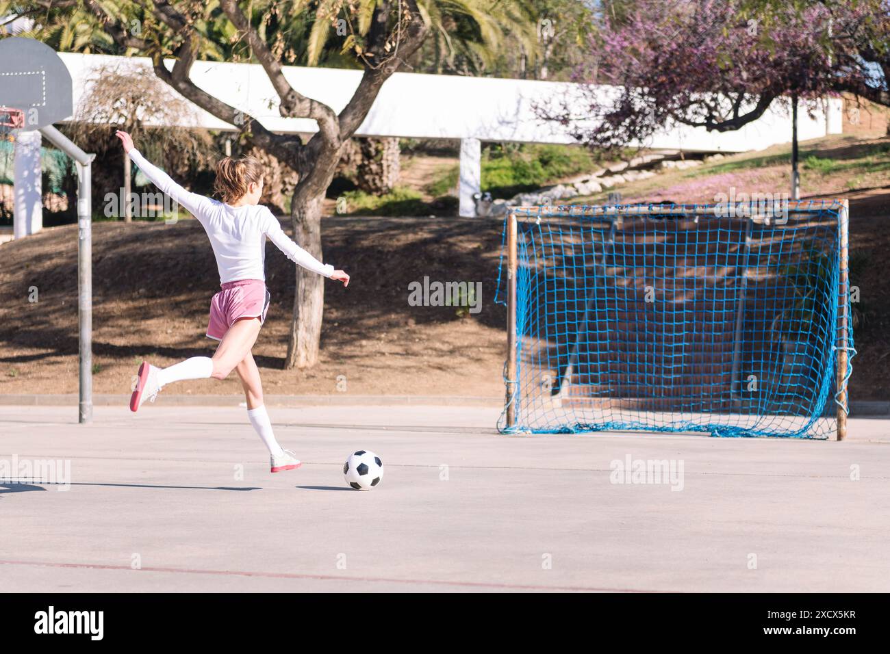 young woman kicking a soccer ball into the goal Stock Photo - Alamy