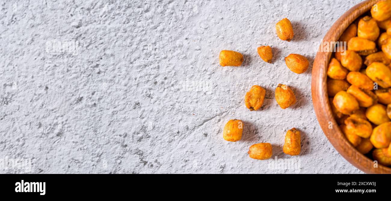 Roasted corn nuts with sauce in wooden bowl on white stone table Stock Photo