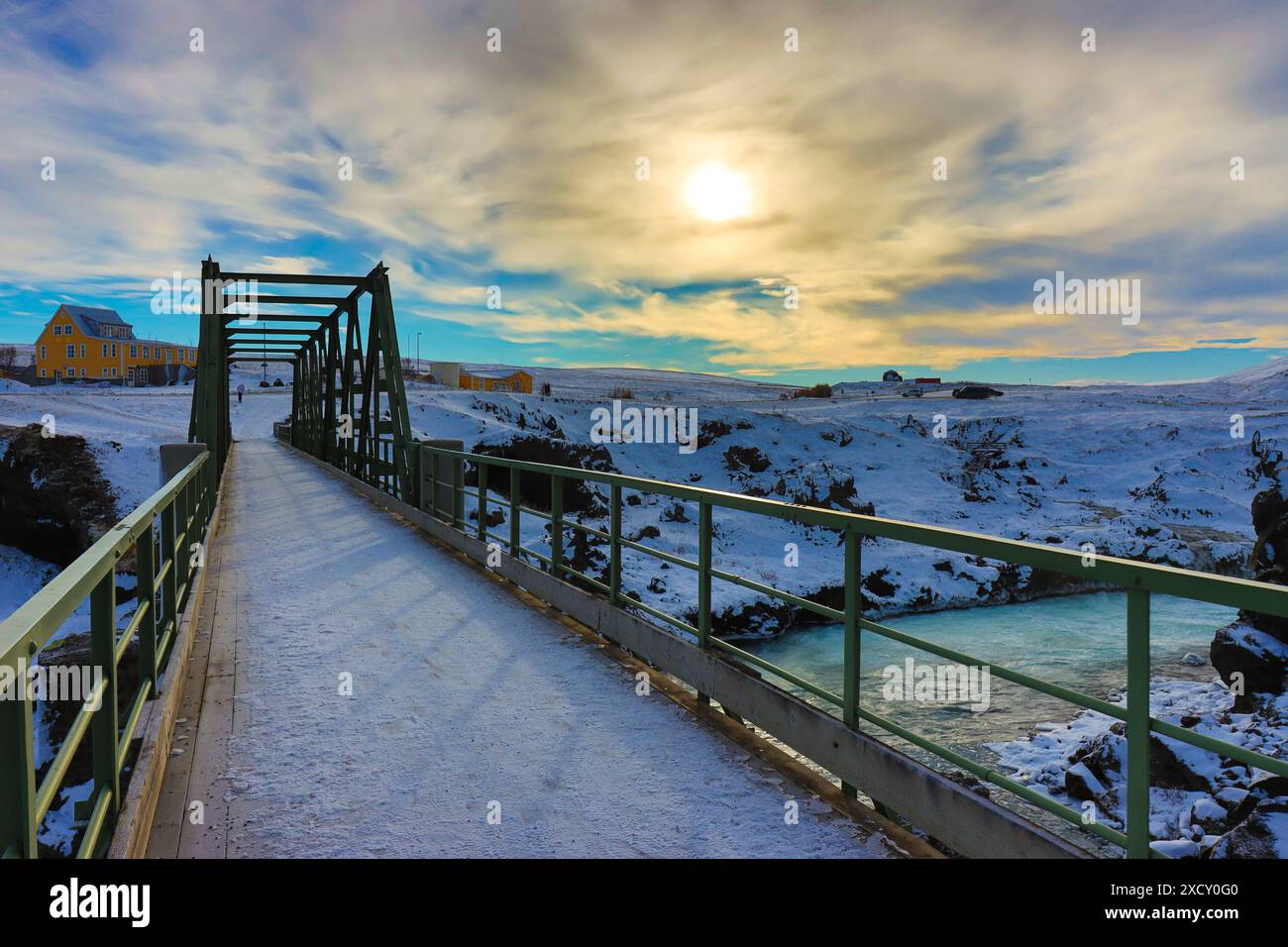 winter landscape of a snowy bridge passing over a waterfall stream in ...