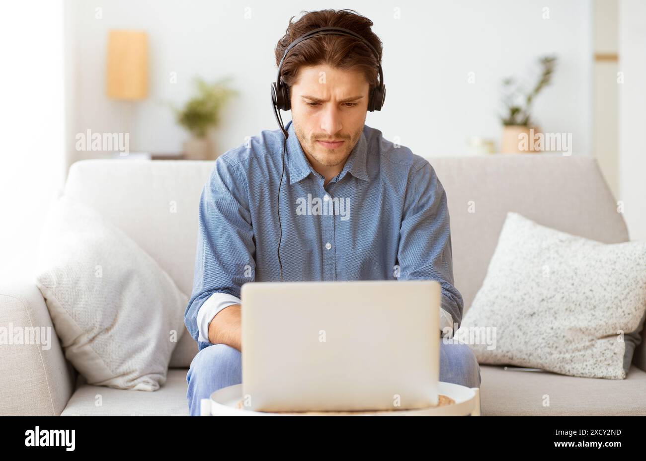Man Working On Laptop While Wearing Headphones Stock Photo
