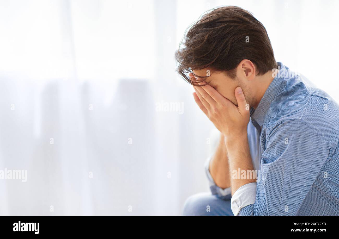 Man Covering Face With Hands in Sadness Stock Photo