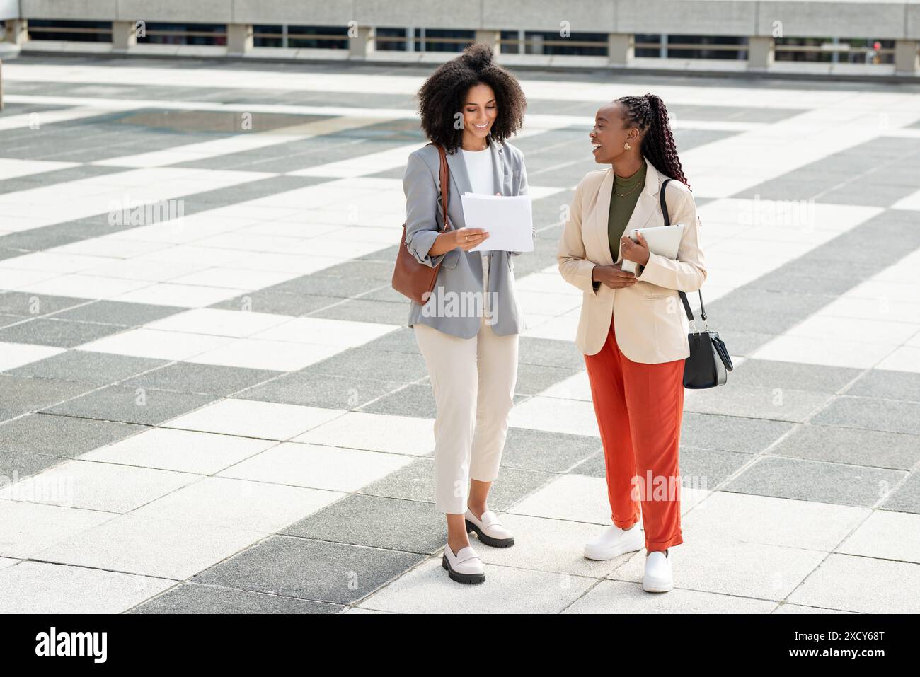 Smiling Black Businesswomen Discussing Documents Outdoors in Professional Attire Stock Photo
