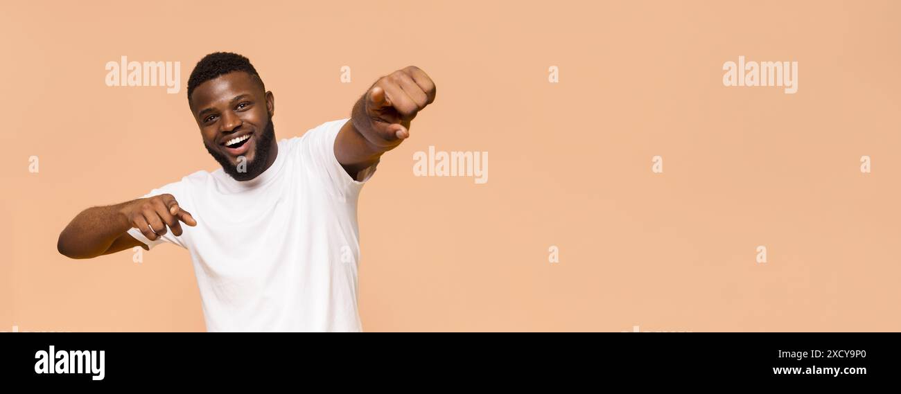 Happy Young Man Pointing and Smiling Against Beige Background Stock Photo