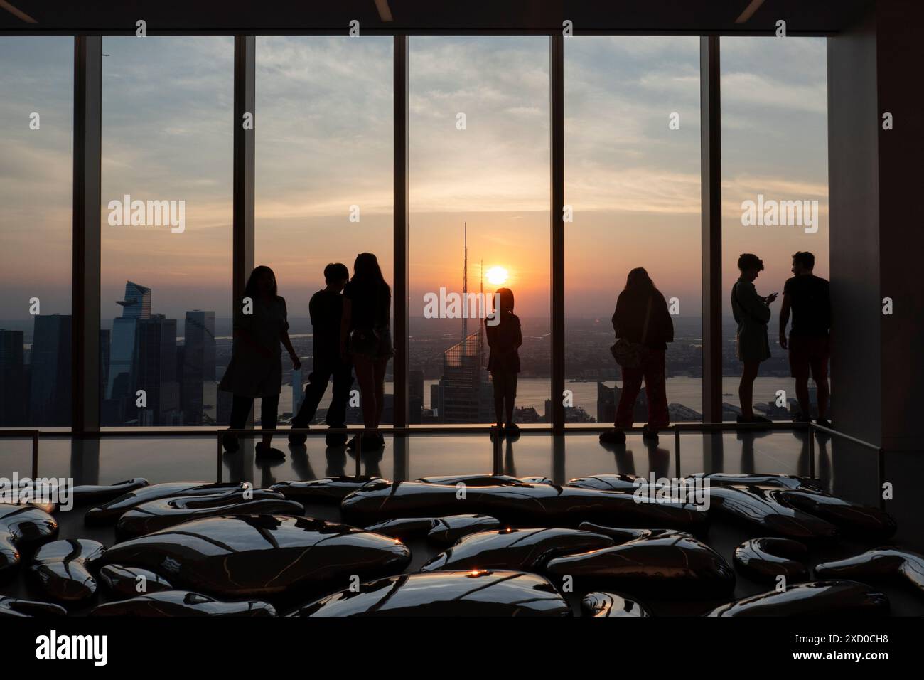People are enjoying the sunset from the Summit One Vanderbilt observation deck in New York, U.S., on Thursday, June 18, 2024. The Summit One Vanderbilt is a veritable wonderland of sensory experiences. Kenzo Digital, the artist who designed each room, uses mirrors to reflect and refract the city that surrounds the structure. The attraction takes visitors to the 93rd floor, high above iconic skyscrapers like the Empire State Building and the Chrysler Building. Stock Photo
