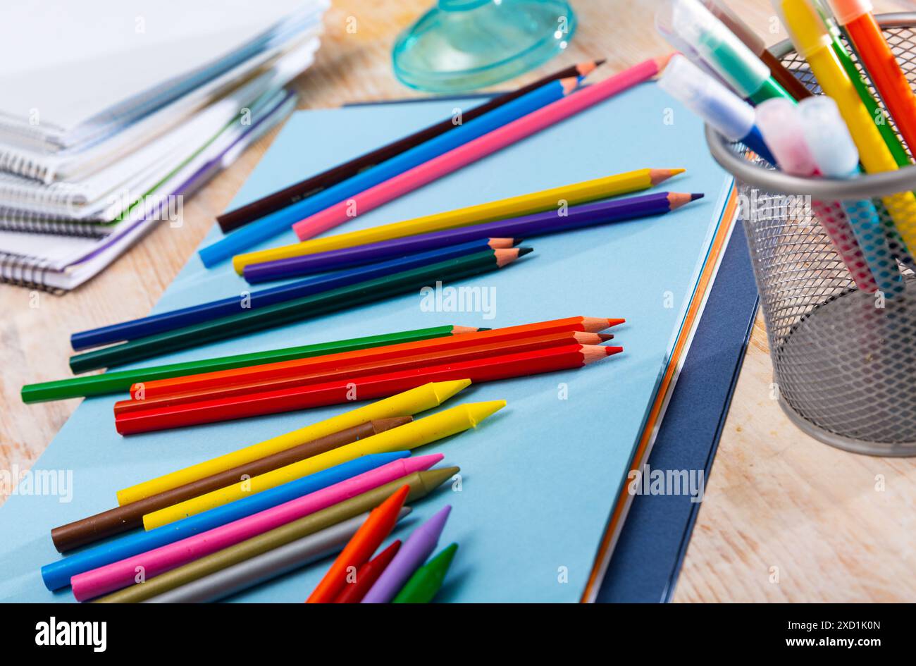 Multicolored pencils on table with papers and notebooks Stock Photo