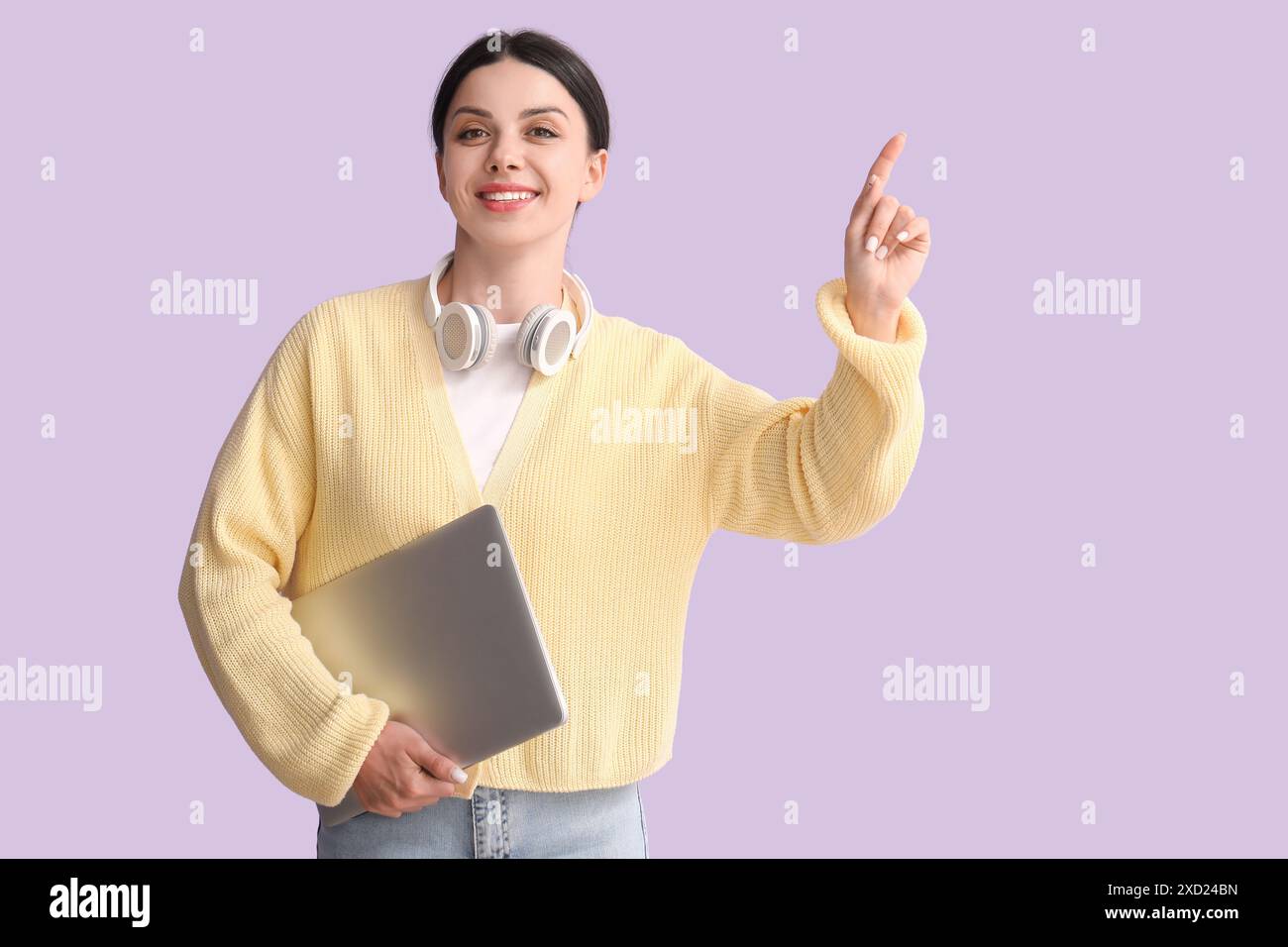Female programmer with laptop pointing at something on lilac background ...