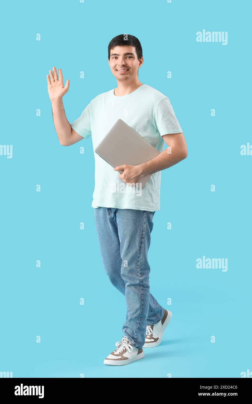 Male programmer with laptop waving hand on blue background Stock Photo ...