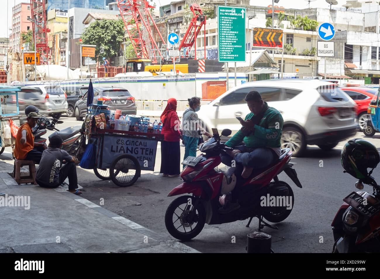 Silhouette of an online motorcycle taxi driver checking his cellphone against the background of a congested highway Stock Photo