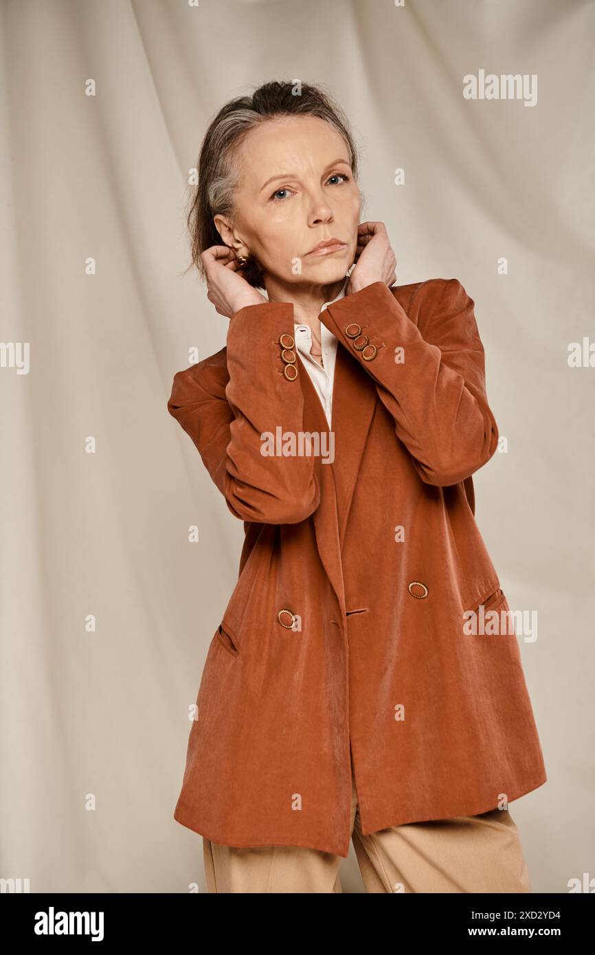 Stylish senior lady in tan blazer and pants poses elegantly while ...