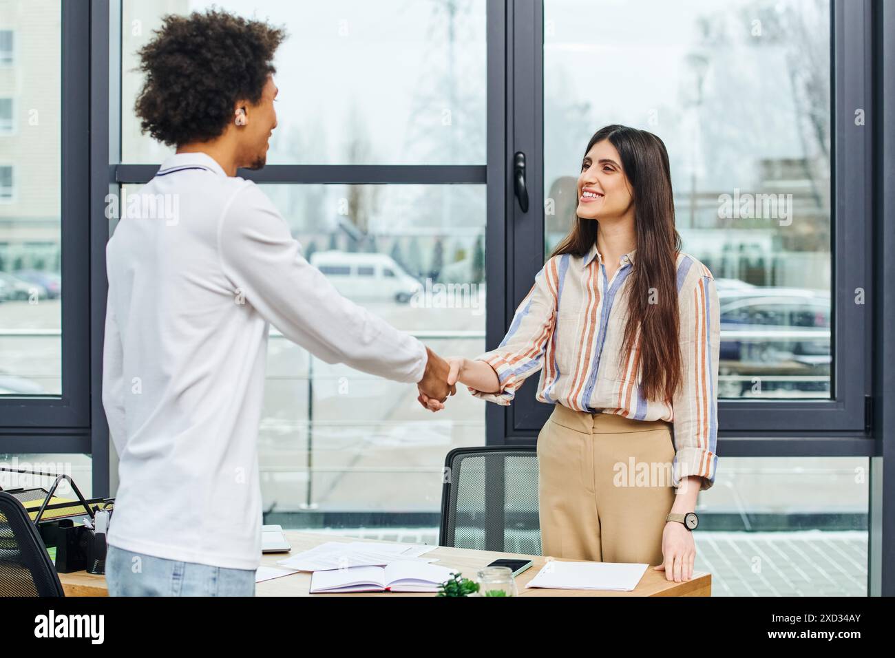 A man and woman shaking hands in an office setting Stock Photo - Alamy