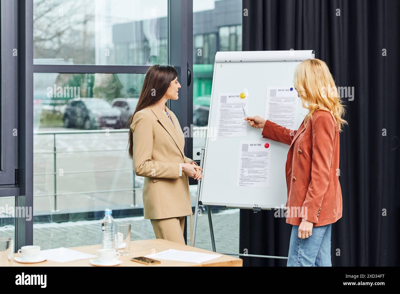 Two business women discussing ideas in front of a whiteboard Stock ...