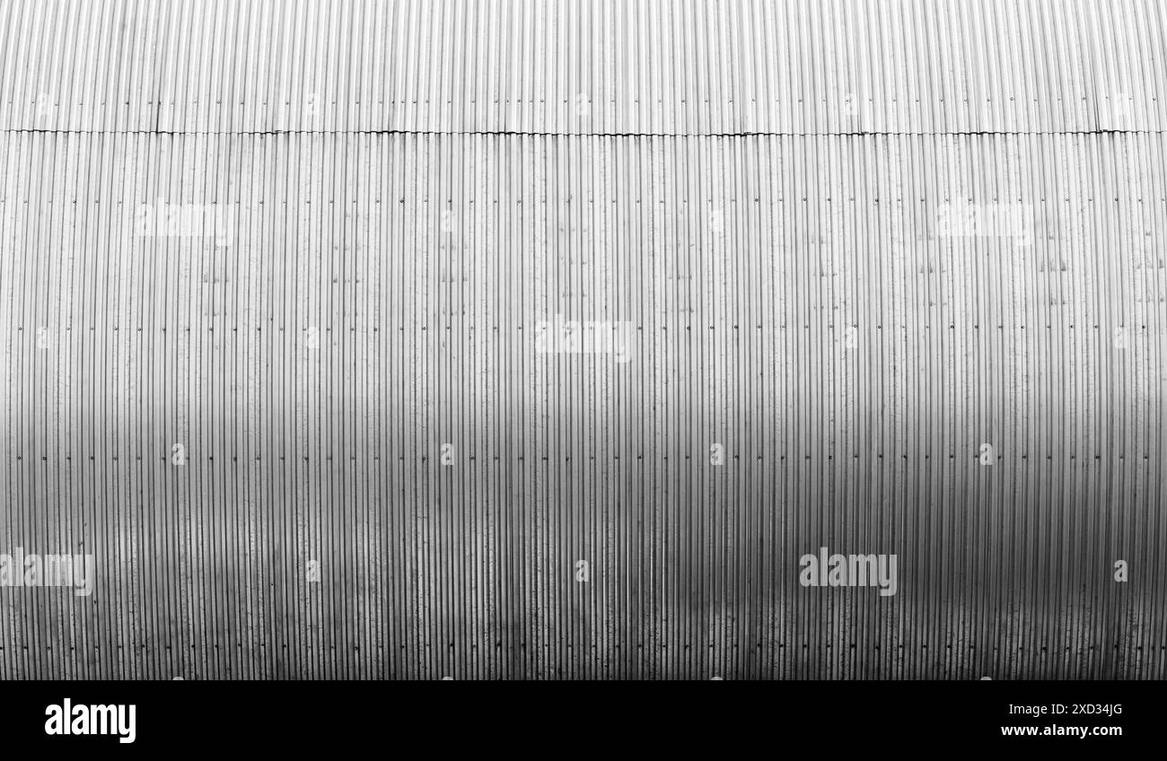 Shiny bent ridged metal wall of a storage building, modern industrial ...