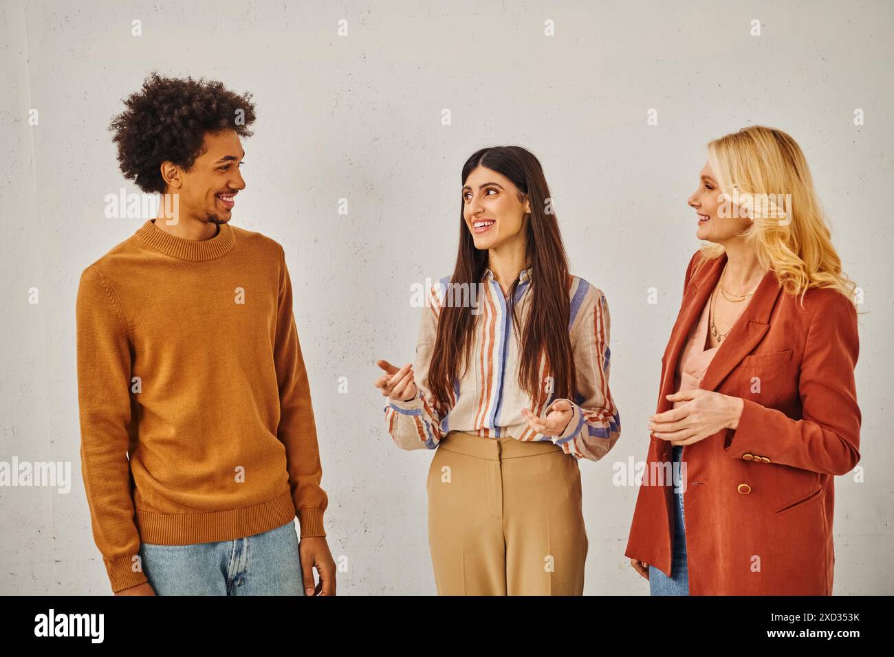 Three individuals engaging in conversation against a blank backdrop. Stock Photo