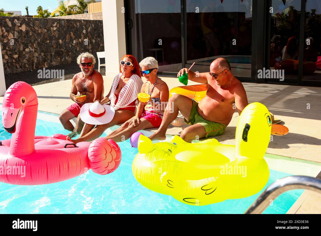A jovial group of seniors having a blast in a swimming pool, lounging ...