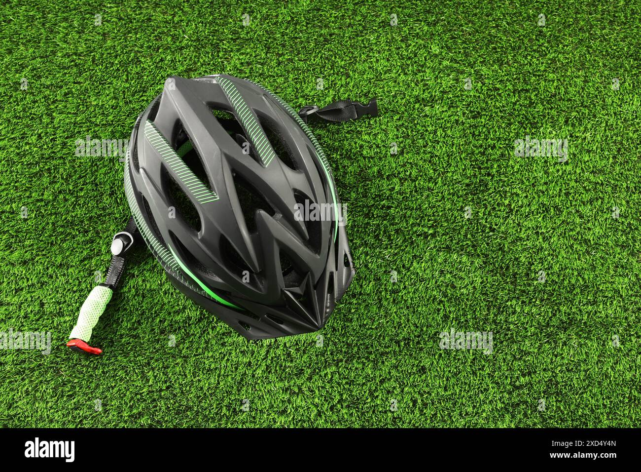Stylish protective helmet on green grass, top view. Space for text ...