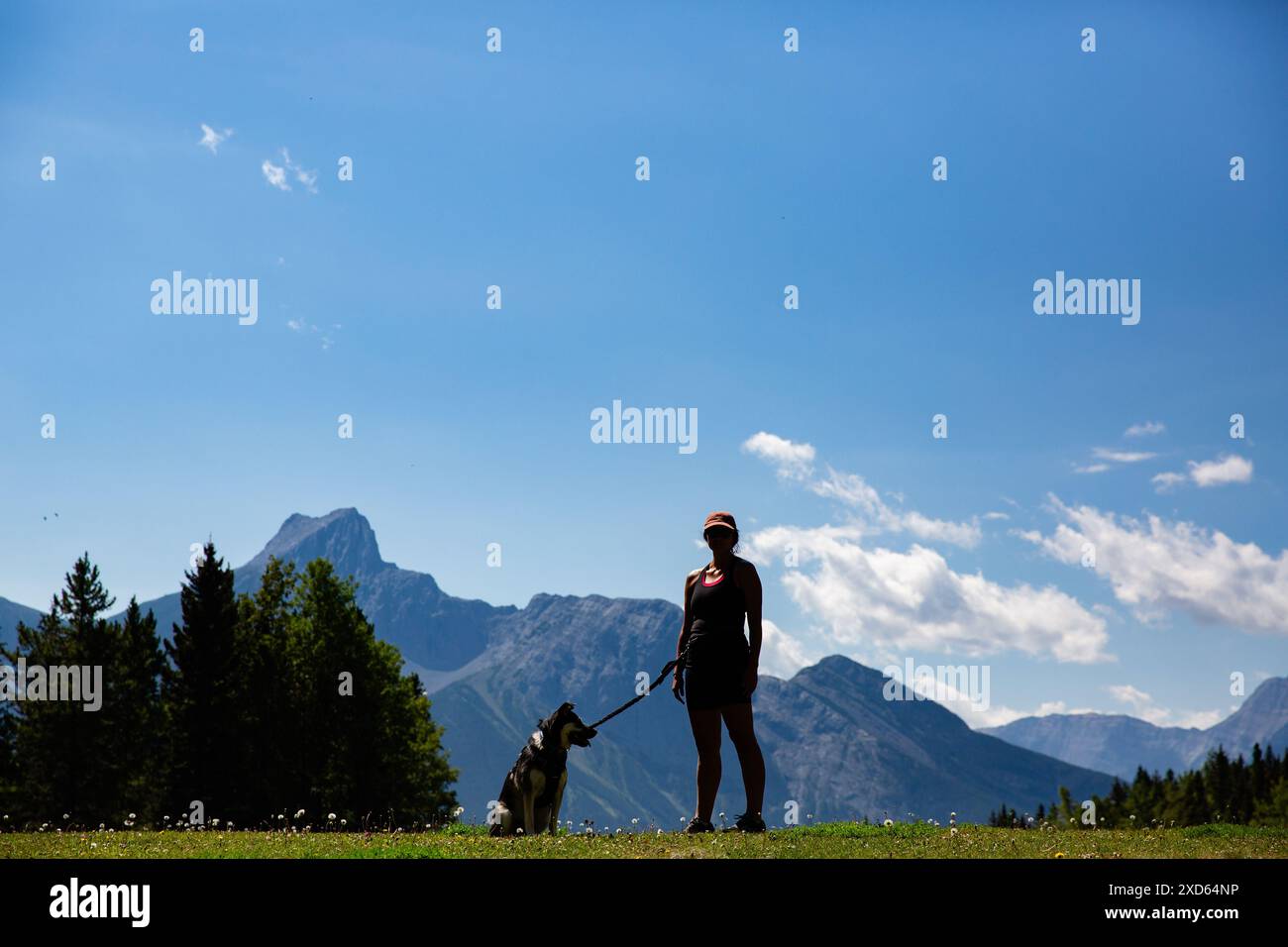 A woman and her mixed breed, german shepherd husky dog in silhouette on a hike in Kananaskis country a popular provincial park in Alberta, Canada Stock Photo