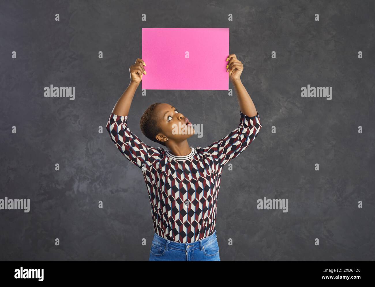 Funny dark skinned woman looking at a pink blank sheet of paper that ...