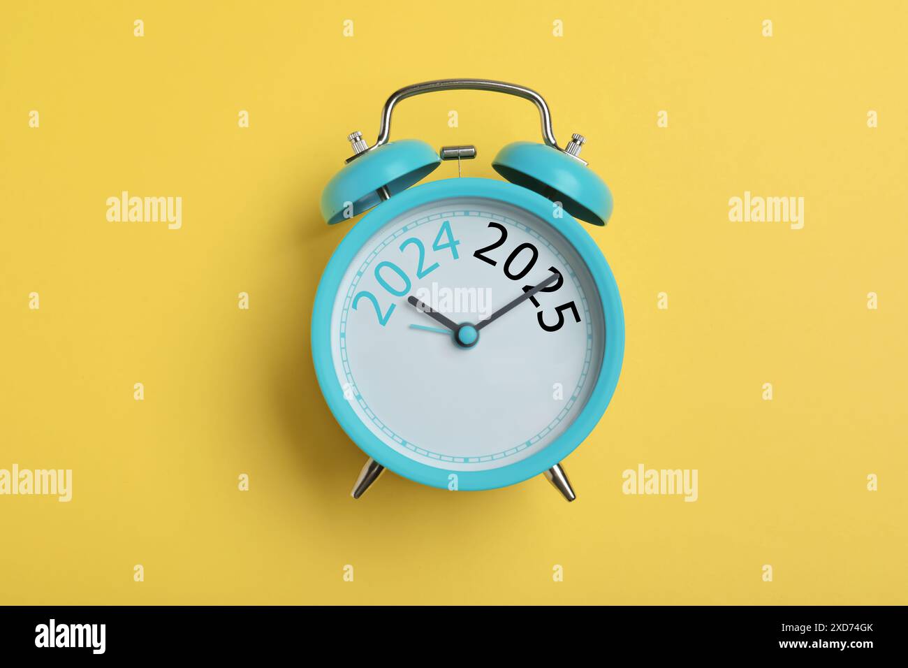 Alarm clock with hands pointing at numbers 2024 and 2025 on yellow