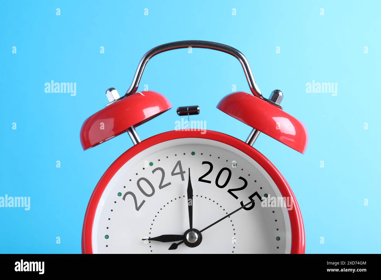 Red alarm clock with numbers 2024 and 2025 on light blue background