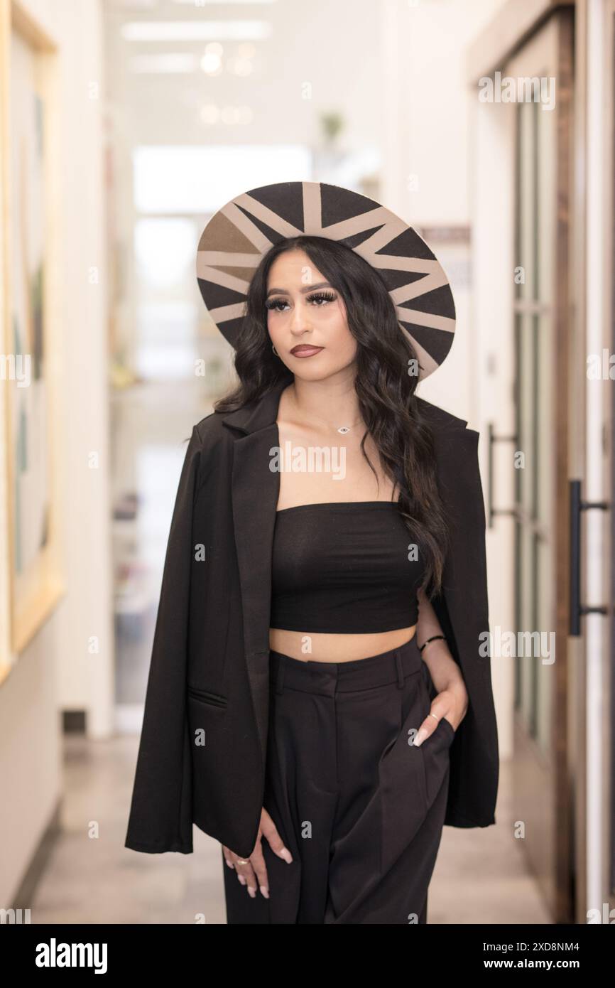 Hispanic woman walking wearing stylish clothes and wearing hat Stock Photo