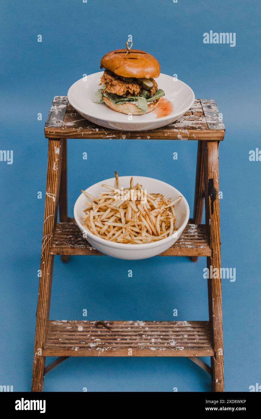 fried chicken sandwich with fries on wood ladder with blue Stock Photo ...