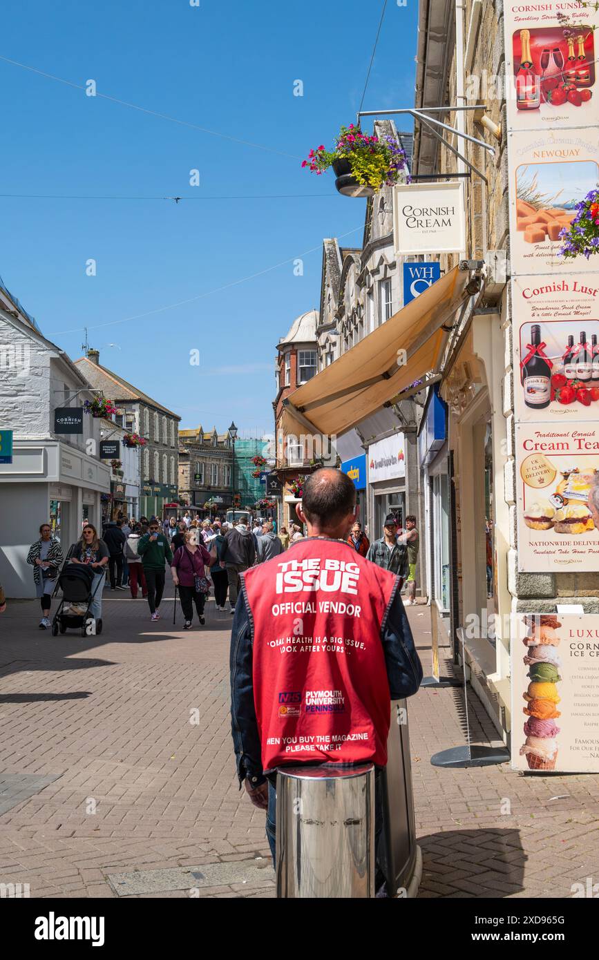 A Big Issue official seller official vendor  standing working in Newquay Town Centre in Cornwall in the UK. Stock Photo