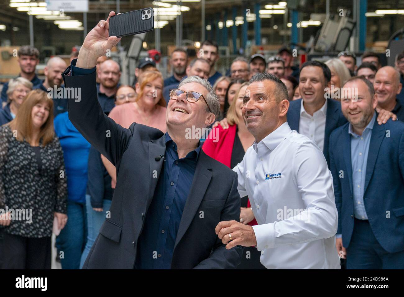 Labour Party leader Sir Keir Starmer takes a selfie alongside Chief Operating Officer Martin Linden and staff during a visit to Window Supply Company in Bathgate, West Lothian, to campaign on Labour's plans to boost jobs and growth across Scotland, while on the General Election campaign trail. Picture date: Friday June 21, 2024. Stock Photo
