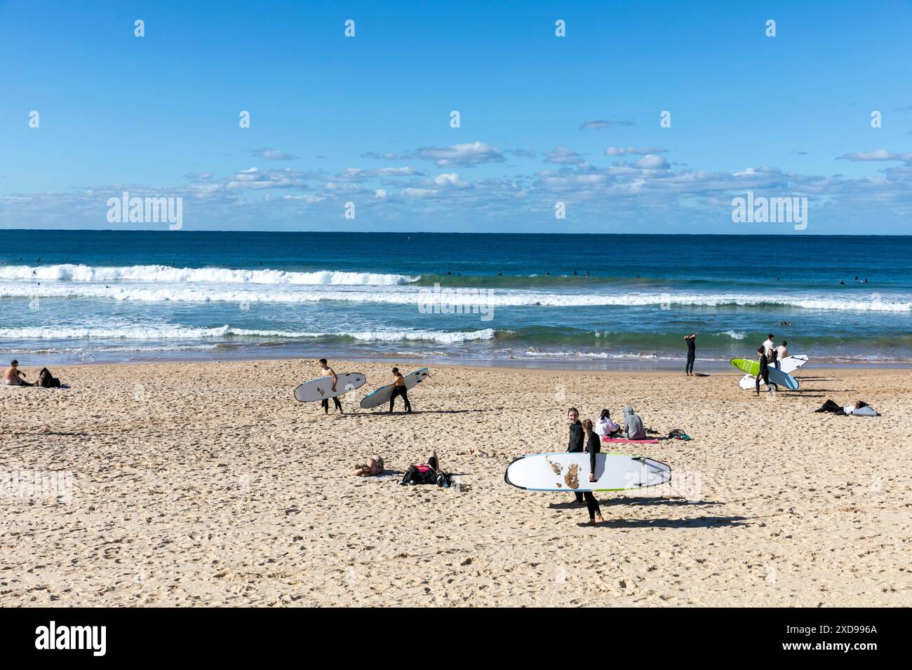 Manly Beach in Sydney, busy with surfers on the beach carrying