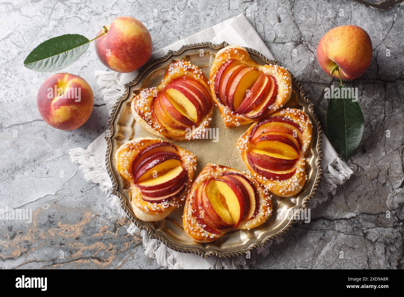 Summer dessert peach puff heart cake with ripe fruits and jam close-up in a plate on the table. Horizontal top view from above Stock Photo