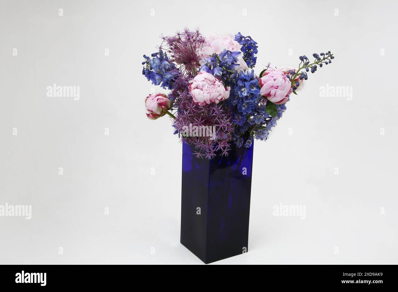 Bouquet of flowers with Peonies in a Blue Glass Rectangle Vase Stock Photo