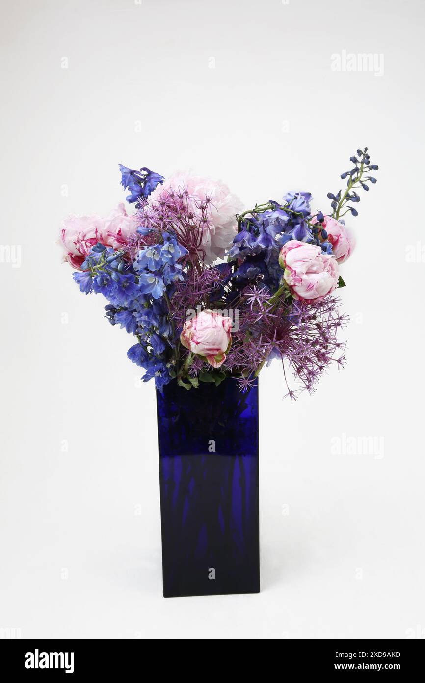 Bouquet of flowers with Peonies in a Blue Glass Rectangle Vase Stock Photo