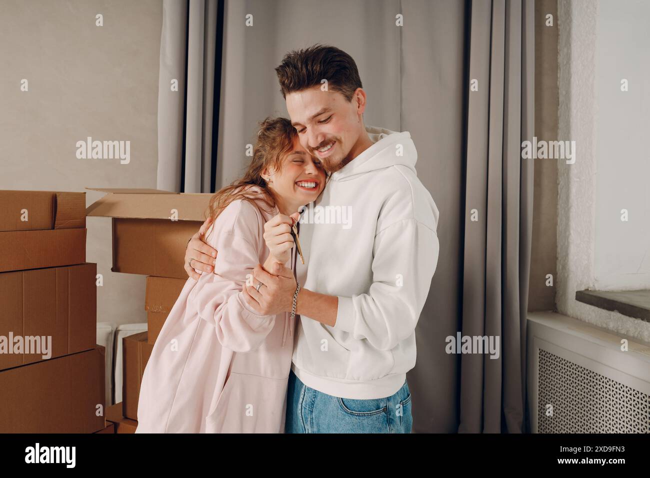 Happy young family couple man and woman hugging and holding key from ...