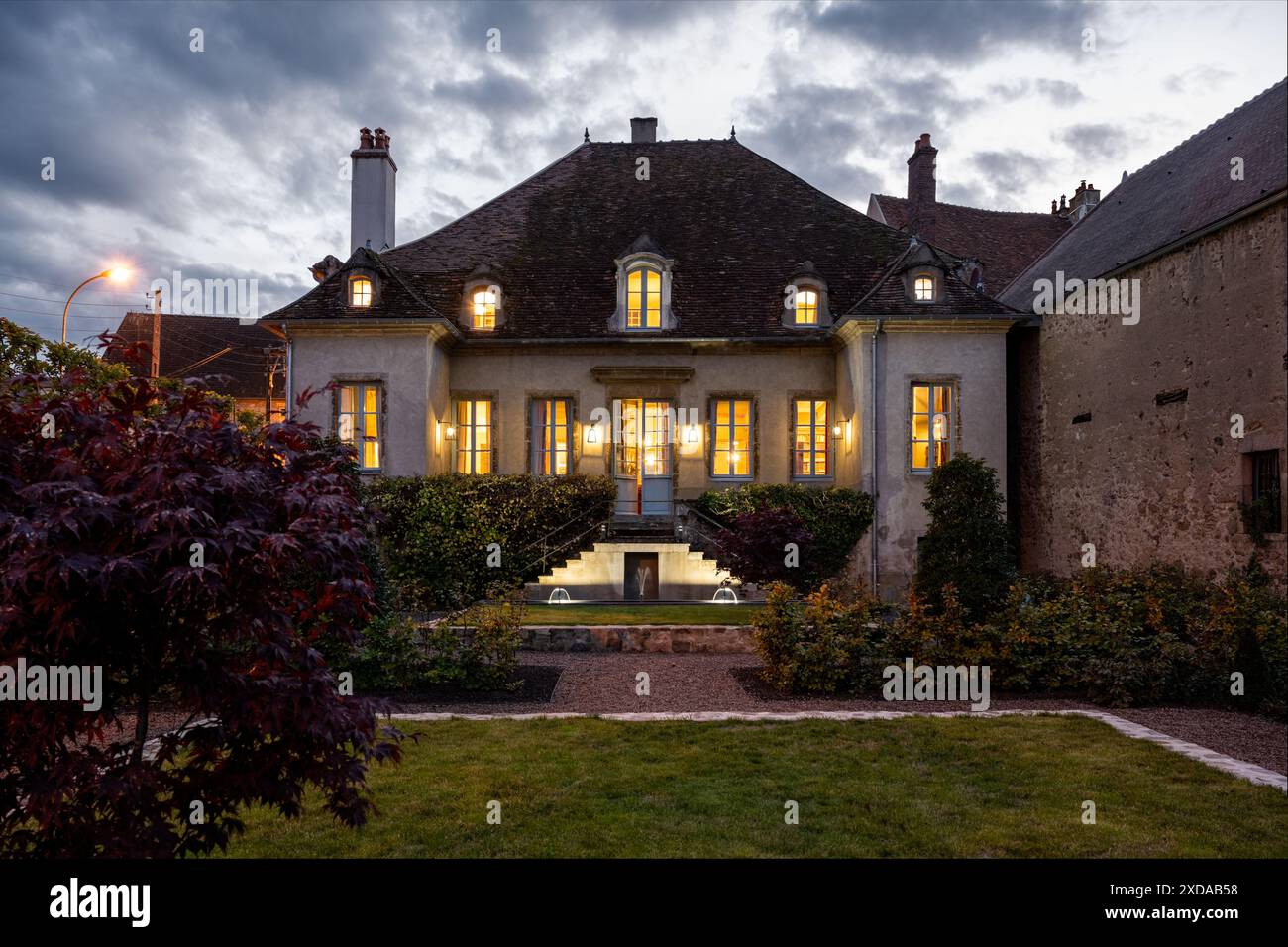 Lit facade at dusk. Renovated stone-built hotel particulier dating from 1770 in Saulieu, Burgundy, France. Stock Photo